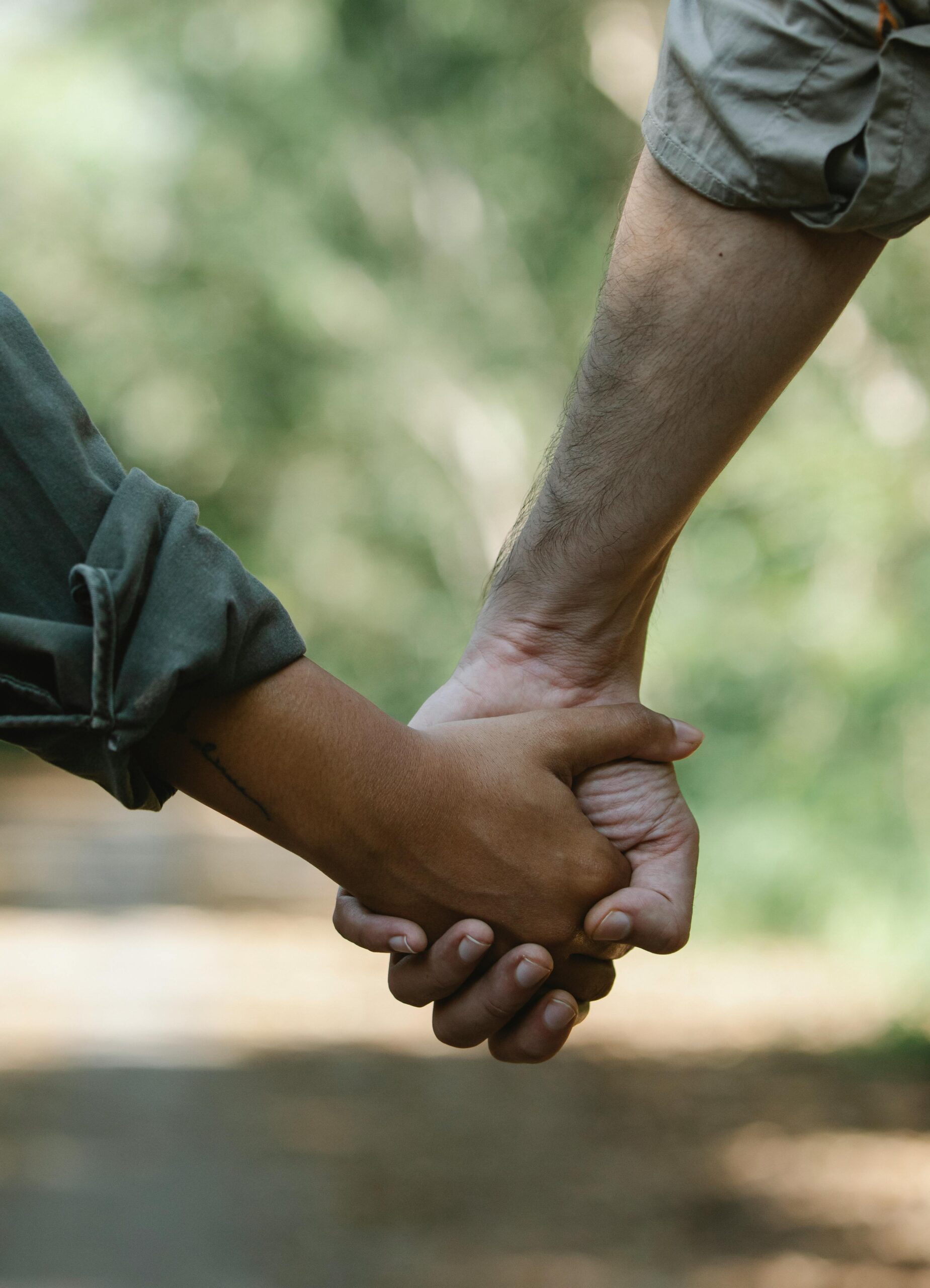 A couple holds hands while walking outdoors, showcasing affection and unity.
